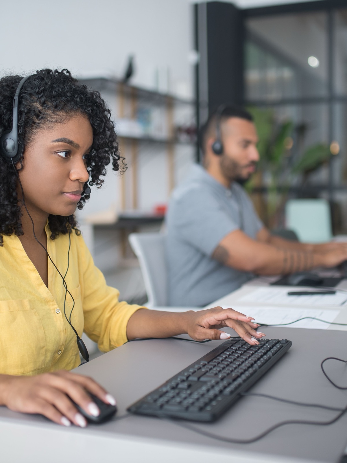 Grand call center agents wearing headsets while working at computers.