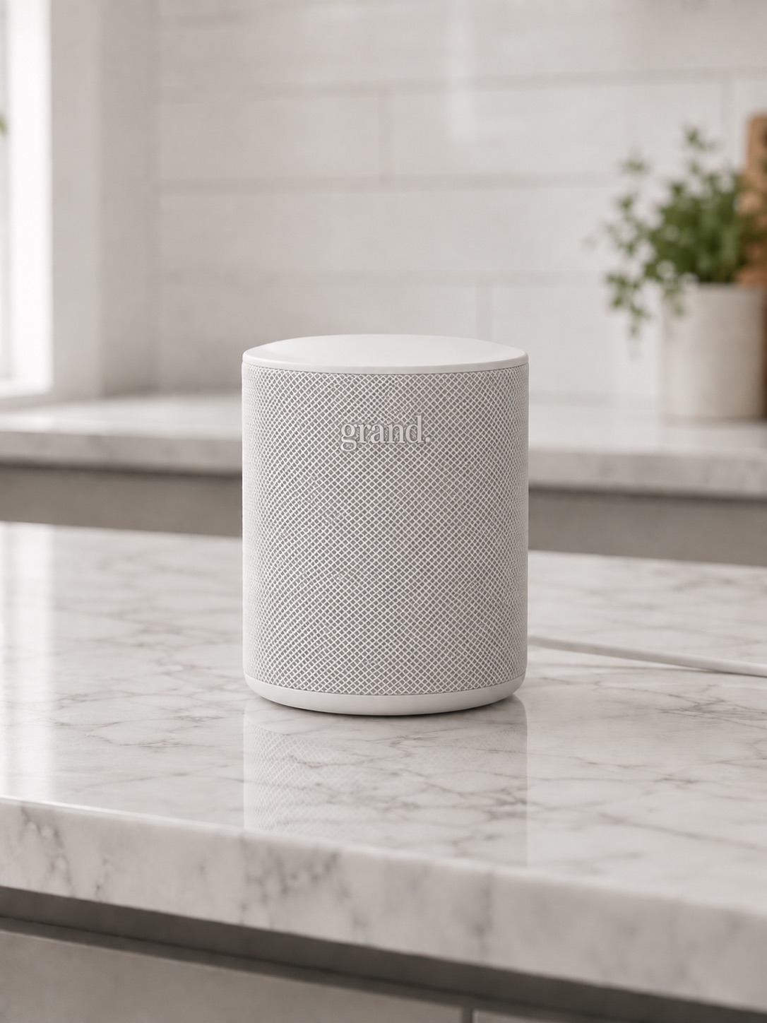 The Grand hub, a small fabric-covered device, on a kitchen counter.